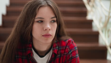 mujer con expresión triste en la escalera. dama bonita con pensamientos negativos se sienta en la escaleras del edificio de cerca. mujer camina a través de un período difícil de la vida