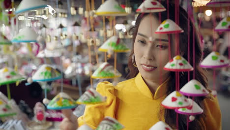 woman in yellow ao dai admiring colorful souvenirs in hoi an market, vibrant culture scene