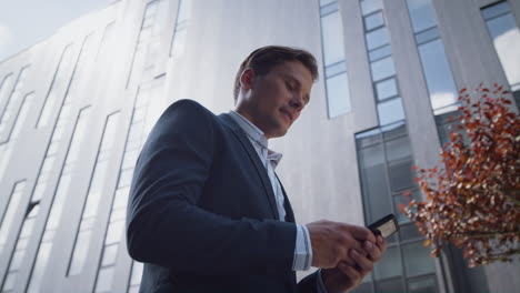 Successful-businessman-using-smartphone-going-in-downtown-district-close-up.