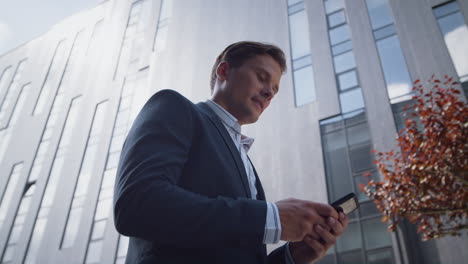 successful businessman using smartphone going in downtown district close up.