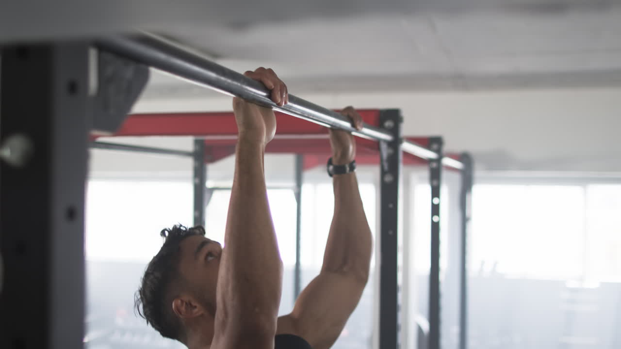Exercising on pull-up bar, man doing pull-ups in gym