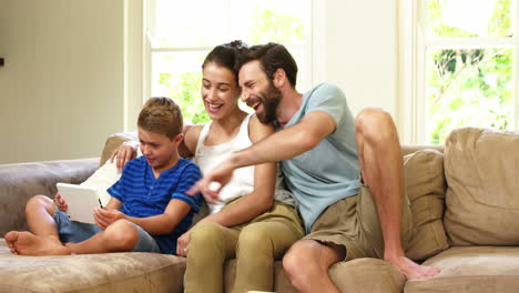 Linda-Familia-Sentada-En-Un-Sofá-Y-Mirando-Una-Tableta