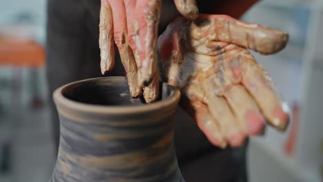 potter shaping a clay pot by hand