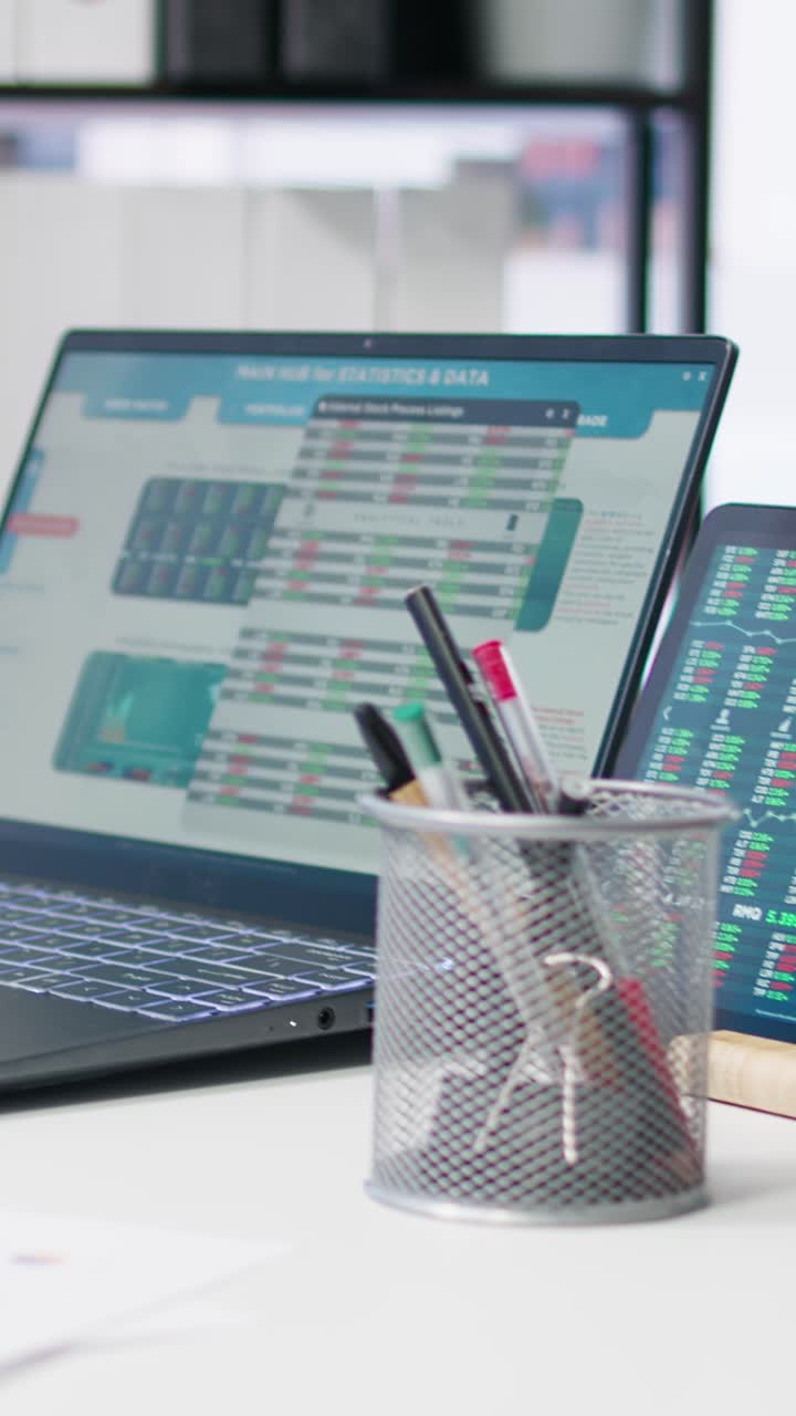 Vertical video Stock market values going up and down on laptop in empty office