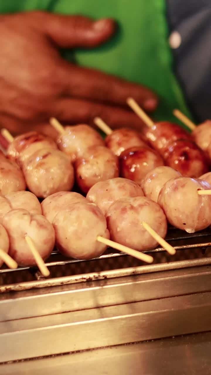 Myyjä grillaamassa makkaroita kelluvalla torikojulla