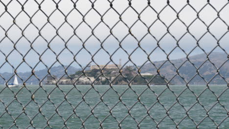 Stahldrahtzaun-Mit-Der-Insel-Alcatraz-Im-Fokus-Im-Hintergrund