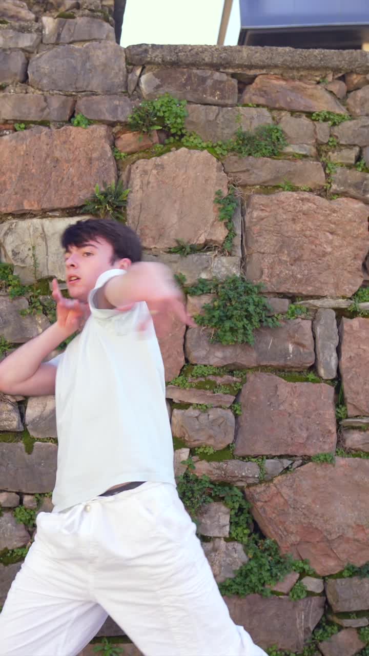 Man dancing by a stone wall