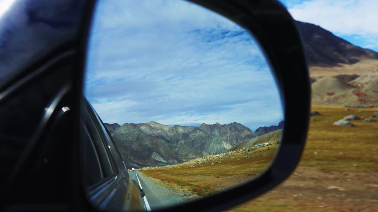 View of mountains in car mirror