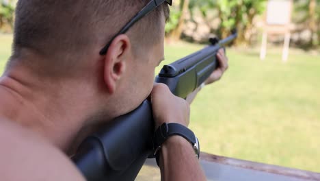 man aiming a rifle at an outdoor shooting range