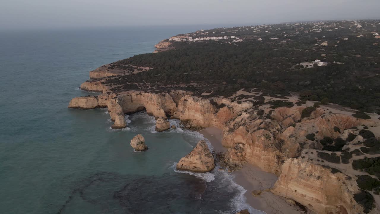 Circular drone shot showing land and ocean near Marinha Beach and Benagil's natural rock arches