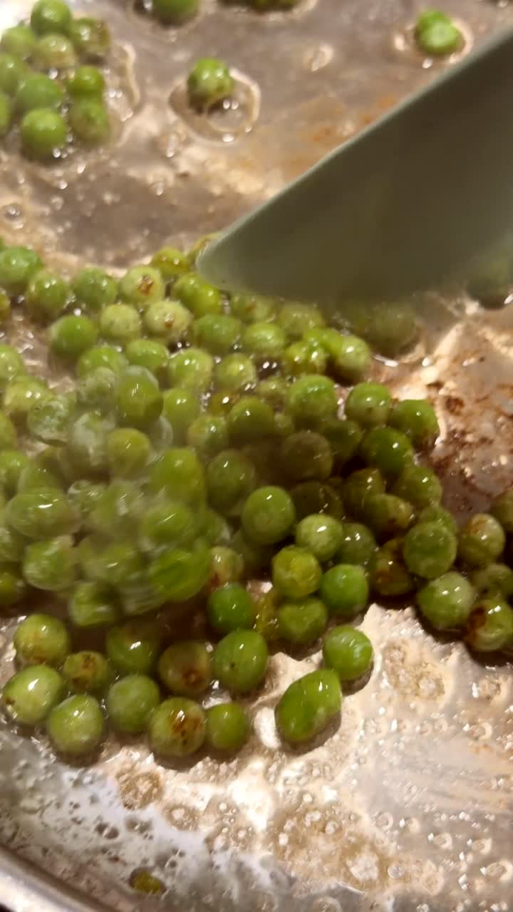 Närbild av gröna ärtor som kokar och rörs om i en panna