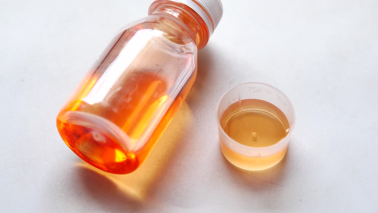 병과 측정 컵에 담긴 액체 약물