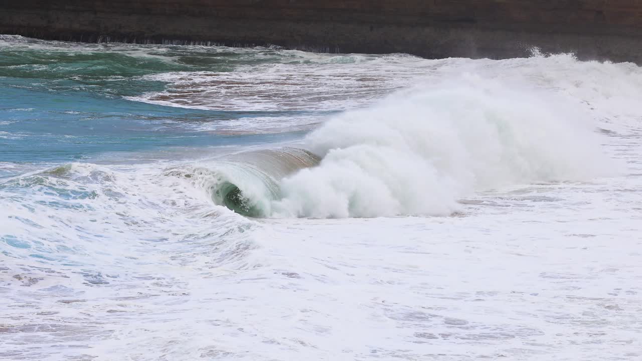 Dynamic ocean waves crash against the rocky shoreline at Port Campbell, Australia, under natural daylight, captured in a 15-second sequence