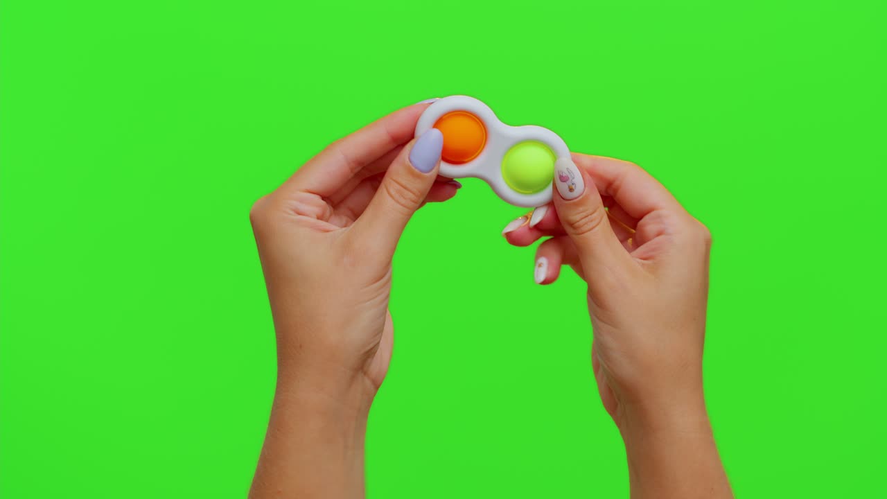 manos que sostienen burbujas de silicona coloridas juguete sensorial simple hoyuelo aislado en el fondo de la llave de croma