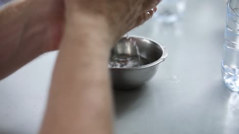 close-up shot of a person cleaning their hands in a bowl of water prior to eating a meal with their hands