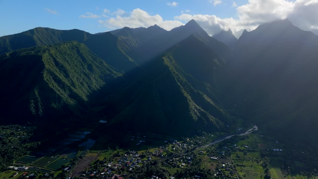 teahupoo pueblo de tahití tarde vista aérea de drone costa de la bahía de la polinesia francesa nubes azules wsl surfing lugar olímpico de verano ciudad pueblo picos de montaña surfista ola arrecife hacia adelante hacia abajo movimiento