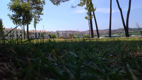 children with their mother playing in the landscaped park with trees in front of the residential buildings on a sunny summer afternoon, blocked panoramic shot