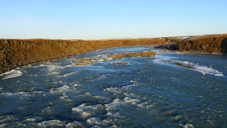 aerial view of frozen urriðafoss waterfall in iceland with wild river