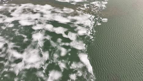 aerial contrast of cracked ice and unfrozen water surface at skútustaðir on lake mývatn. reykjahlíð, iceland