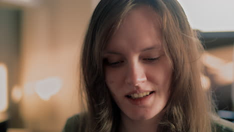 cinematic close up of a young white woman smiling straight into the camera during a golden hour sunrise in her apartment in slow motion