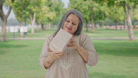 Happy-Indian-old-woman-receiving-a-gift-in-park