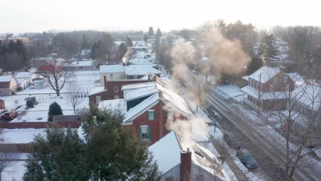 cold winter morning as smoke and steam billow from chimneys of homes in quiet town neighborhood