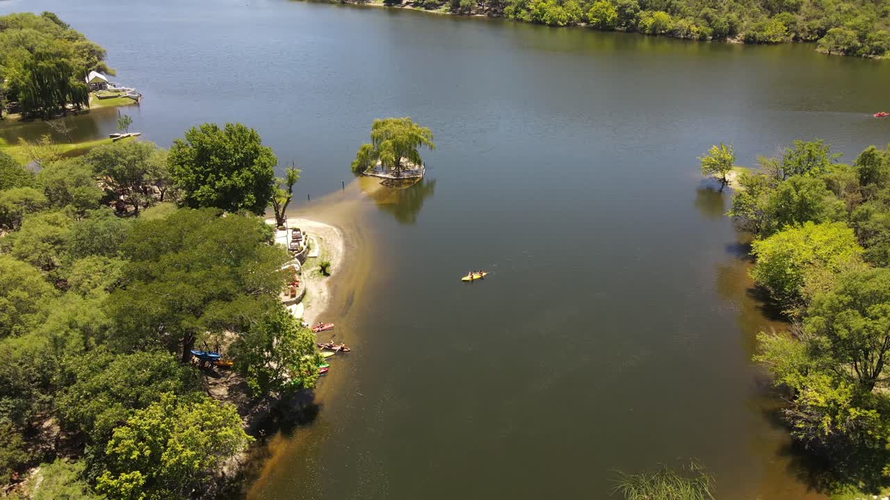 vista aérea del kayak amarillo en el lago remando hasta la playa de arena y la costa en la naturaleza en verano