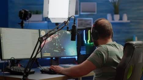 streamer concentrado jugando un videojuego de disparos espaciales usando auriculares