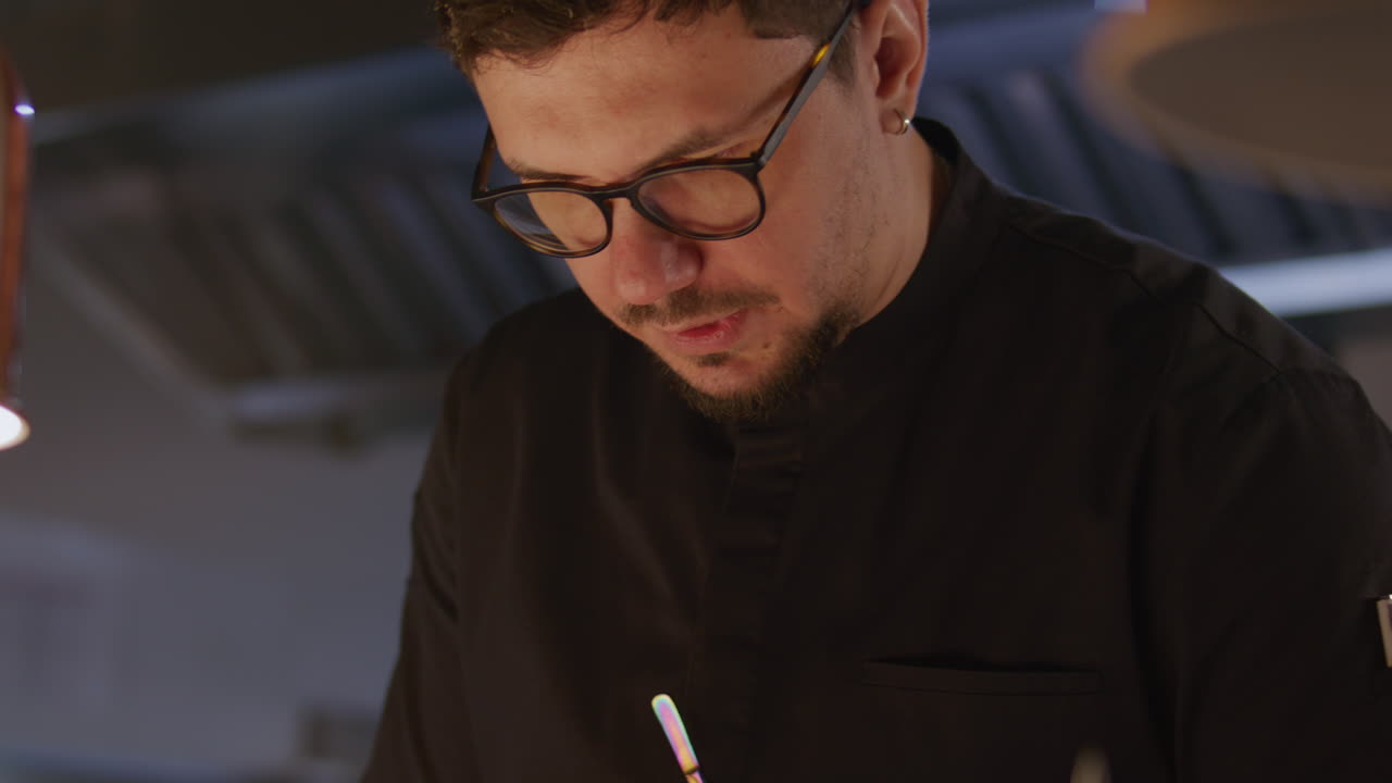 Chef escribiendo comanda mientras gestiona el servicio de cocina del restaurante