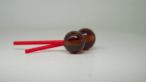 dos piruletas de color marrón en un palo rojo cruzado - primer plano