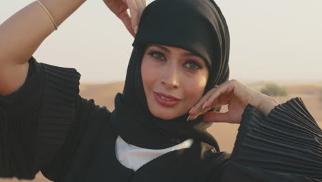 close up portrait of muslim woman wearing hijab and looking at camera in a windy desert