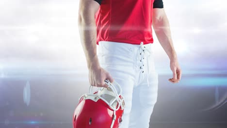 Animation-midsection-of-male-american-football-player-holding-helmet-at-floodlit-stadium