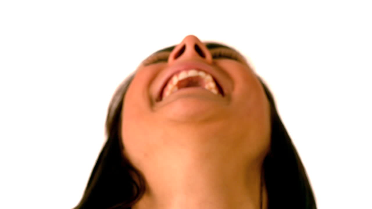 una morena feliz riendo sobre un fondo blanco