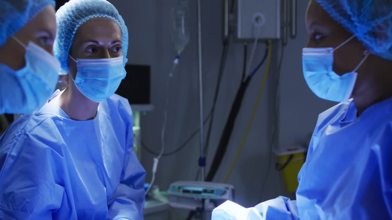 Diverse surgeons wearing surgical caps and face masks in operating theatre in hospital