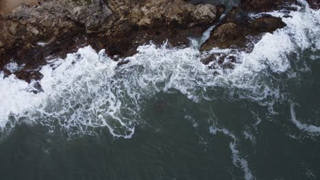 Waves-crashing-against-the-Northumberland-coast---aerial-ascending-shot