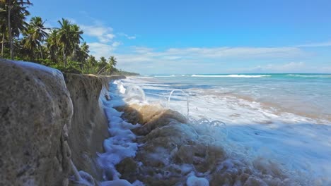 la ola espumosa sube y choca contra la pared arenosa