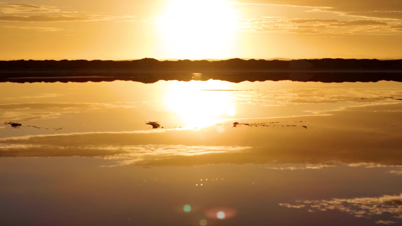 Lavt luftfoto over en saltvandssø, der afslører en opgående sol. Walvis Bay, Namibia.