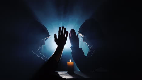 dos hombres encapuchados rezan en la oscuridad en los rayos de luz