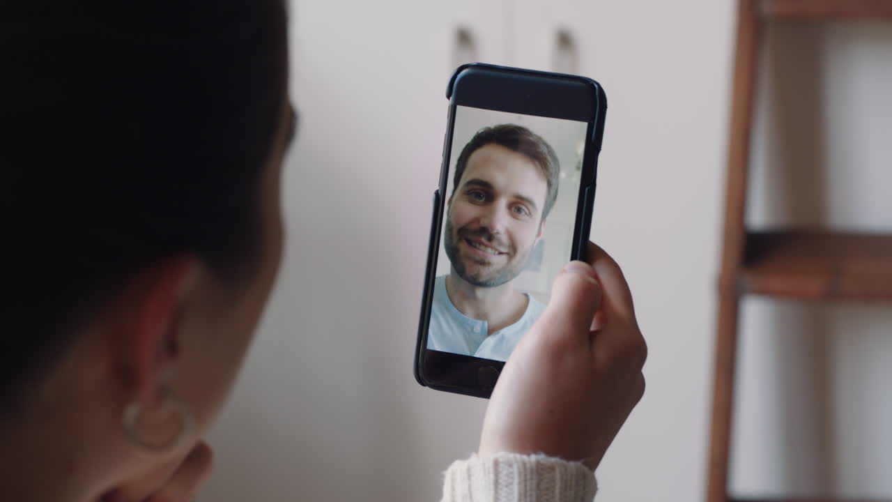 mujer joven teniendo video chat usando teléfono inteligente en casa hablando con su novio mostrando el estilo de vida de compartir apartamento disfrutando de una relación a larga distancia