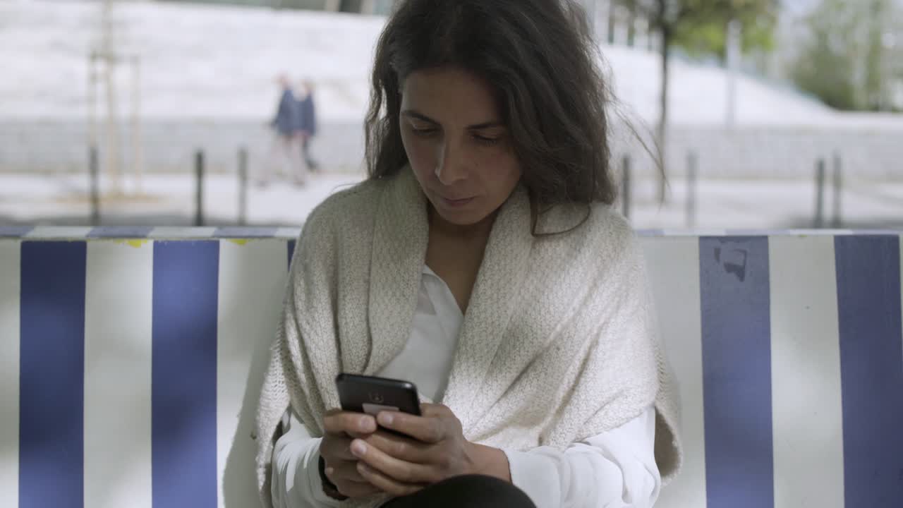 Focused middle aged lady typing message on smartphone.