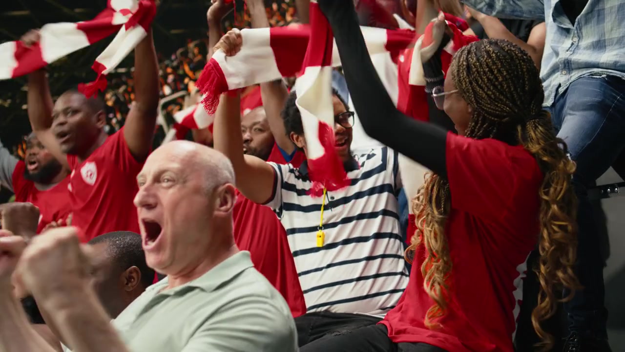 Aficionadas al fútbol celebrando un gol con los brazos en alto en las gradas abarrotadas del estadio.