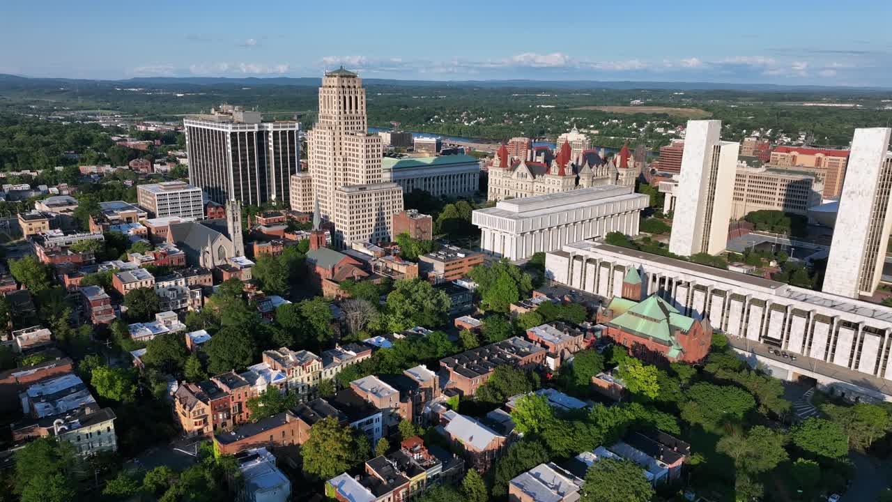 Establishing drone flight over American city of Albany,New York with green trees in summer. Historic townhouses and multi-story buildings.Empire State plaza, office building and downtown in background