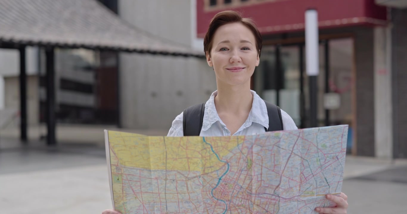 Smiling Woman Tourist Navigating with a Map in the City