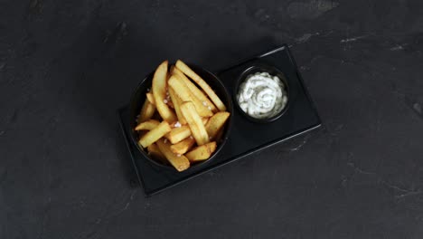 patatas fritas con sal junto a una taza de mayonesa se presentan en un plato giratorio
