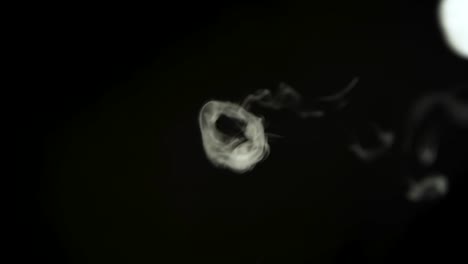 smoke rings of dry ice in motion on a black background. closeup - smoke rings of dry ice in motion on a black background at dark studio. closeup