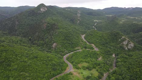 Aerial-view-of-mountains-village-country-road-in-beautiful-green-meadows-mountains