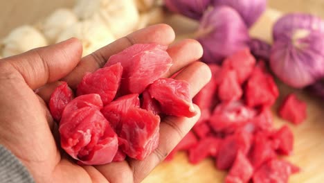 cubos de carne cruda en la mano con verduras