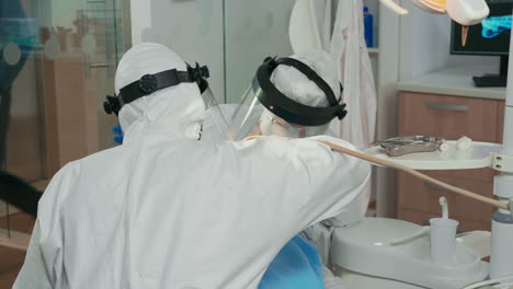 dentistas con escudo facial limpiando y examinando los dientes de los pacientes