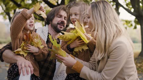 Familia-Feliz-Recogiendo-Hojas-En-La-Temporada-De-Otoño