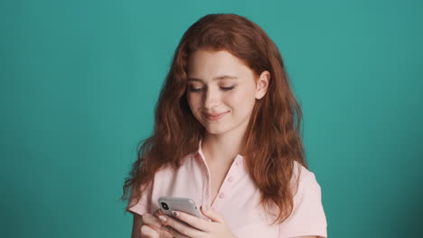 redheaded girl in front of camera on turquoise background.